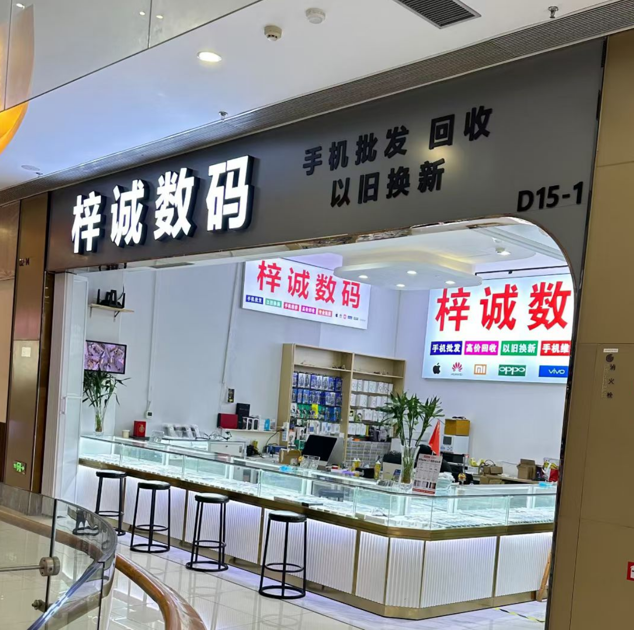 数码店外景，玻璃门面，LED招牌显示店铺名称，门前有停车区域，白天光线充足